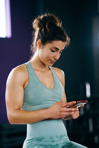 Young woman using mobile phone in gym