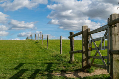 Wooden fence on field against sky