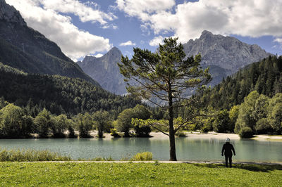Scenic view of person looking at calm lake against mountain range
