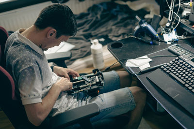 A young man repairs the engine steering wheel on a joystick.