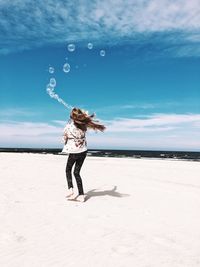 Full length of girl on sand beach against sky