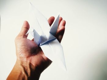 Close-up of hand holding paper against white background