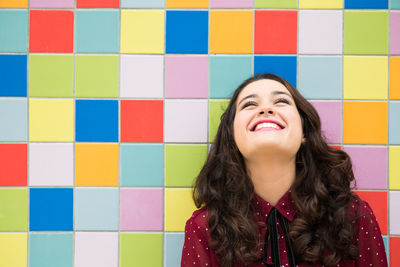 Portrait of a smiling young woman standing against wall