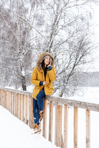 Woman standing on snow covered tree during winter