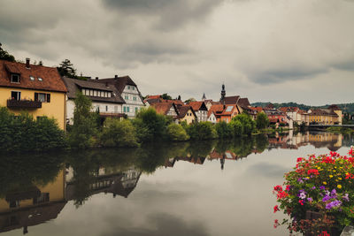 Buildings by river against sky