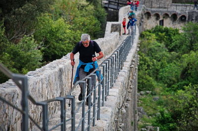 Rear view of man walking on footbridge