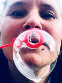 Close-up portrait of mature woman blowing bubble