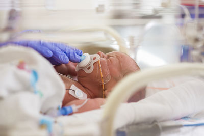 Newborn baby boy with pacifier sleeping in crib at hospital