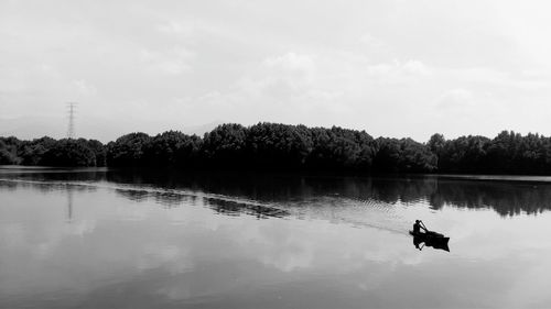 Reflection of man in lake against sky