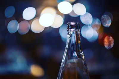 Close-up of bottle against illuminated lights at night