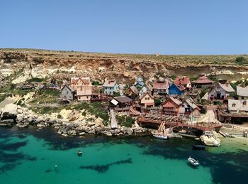 Houses by sea against clear blue sky