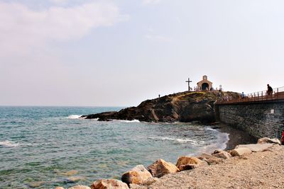 Man on cliff by sea against clear sky