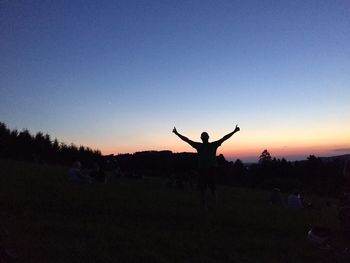 Silhouette of people on landscape at sunset