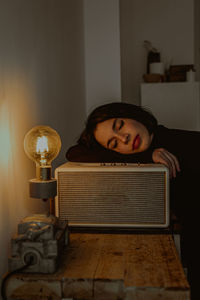 Side view of dreamy female leaning on radio set in retro room and closed eyes