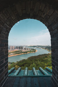 Shot through brick old window with view of cityscape of nanning on river shore, china