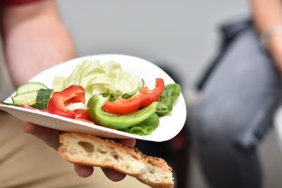 Person holding paper plate with raw vegetable