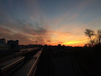 Railroad tracks in city against sky during sunset