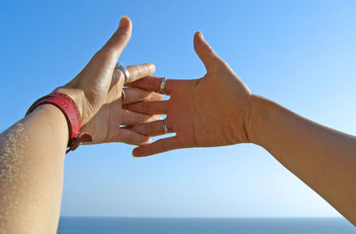 Low angle view of hand joining fingers against clear sky