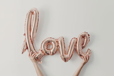 Girl holding shiny balloon with love text in front of wall