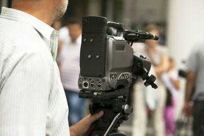 Midsection of cameraman filming with movie camera