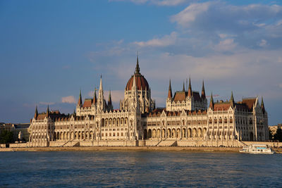 Buildings by river against sky
