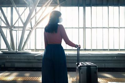 Rear view of woman standing by window