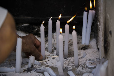 Close-up of hand holding candles against temple