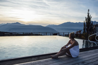 Woman relaxing at the poolside, wrapped in towel