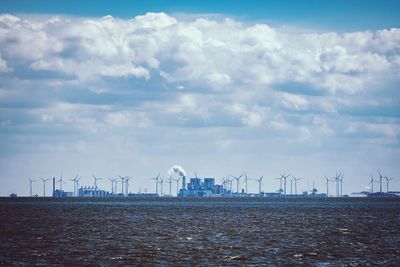 Wind turbines on sea shore against sky