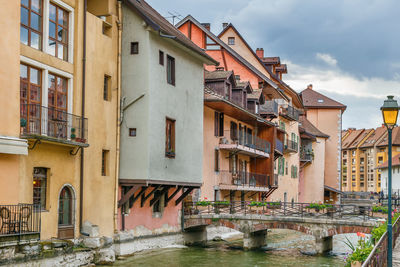 Residential buildings by canal against sky