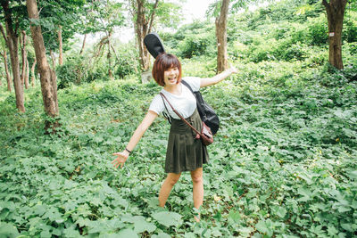 Full length of happy young woman in forest