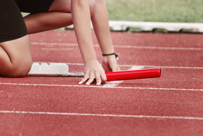 Midsection of woman crouching at starting line of running track