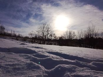 Snow covered landscape against sky during sunset