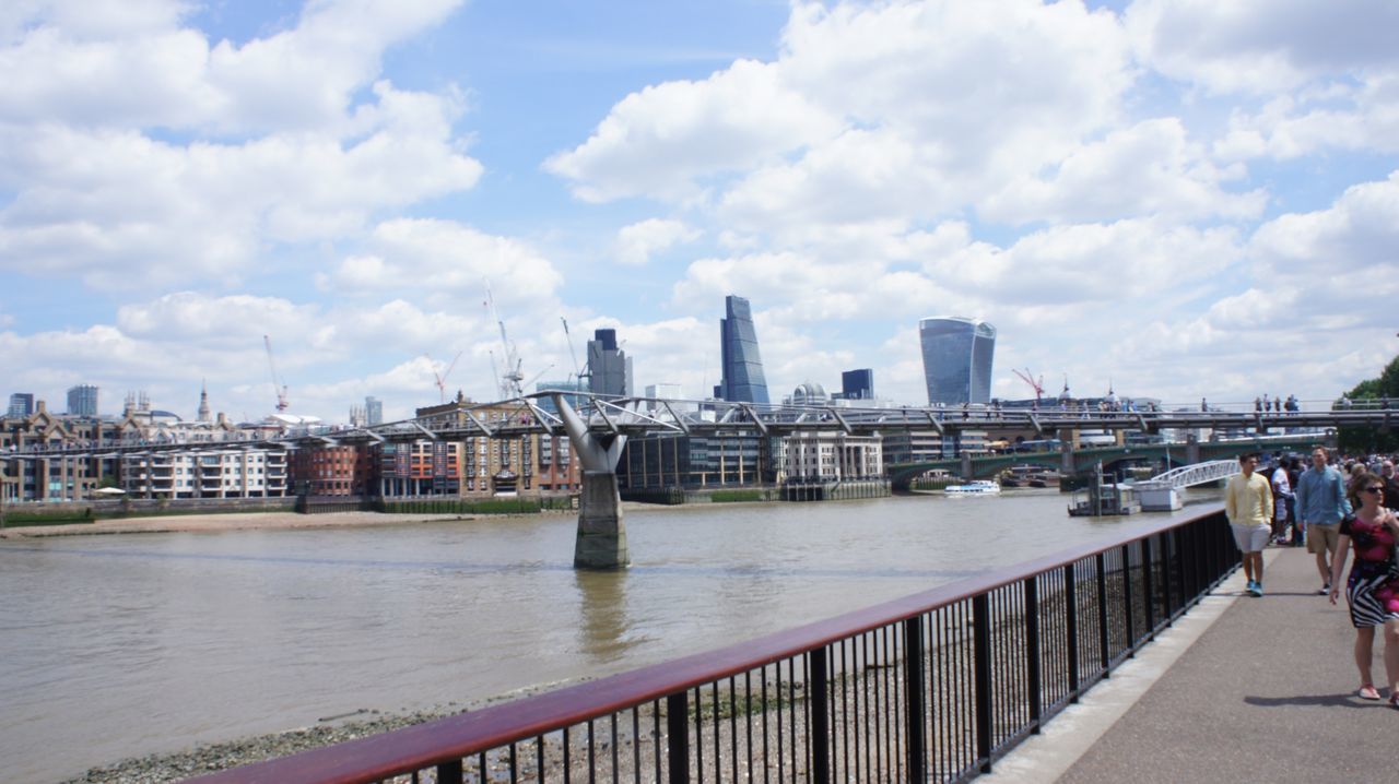 architecture, built structure, building exterior, sky, railing, water, city, river, cloud - sky, men, bridge - man made structure, cloud, person, lifestyles, city life, connection, leisure activity, cityscape