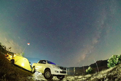 Cars on field against sky at night