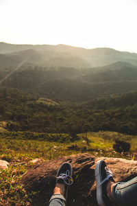 Low section of people on mountain against sky