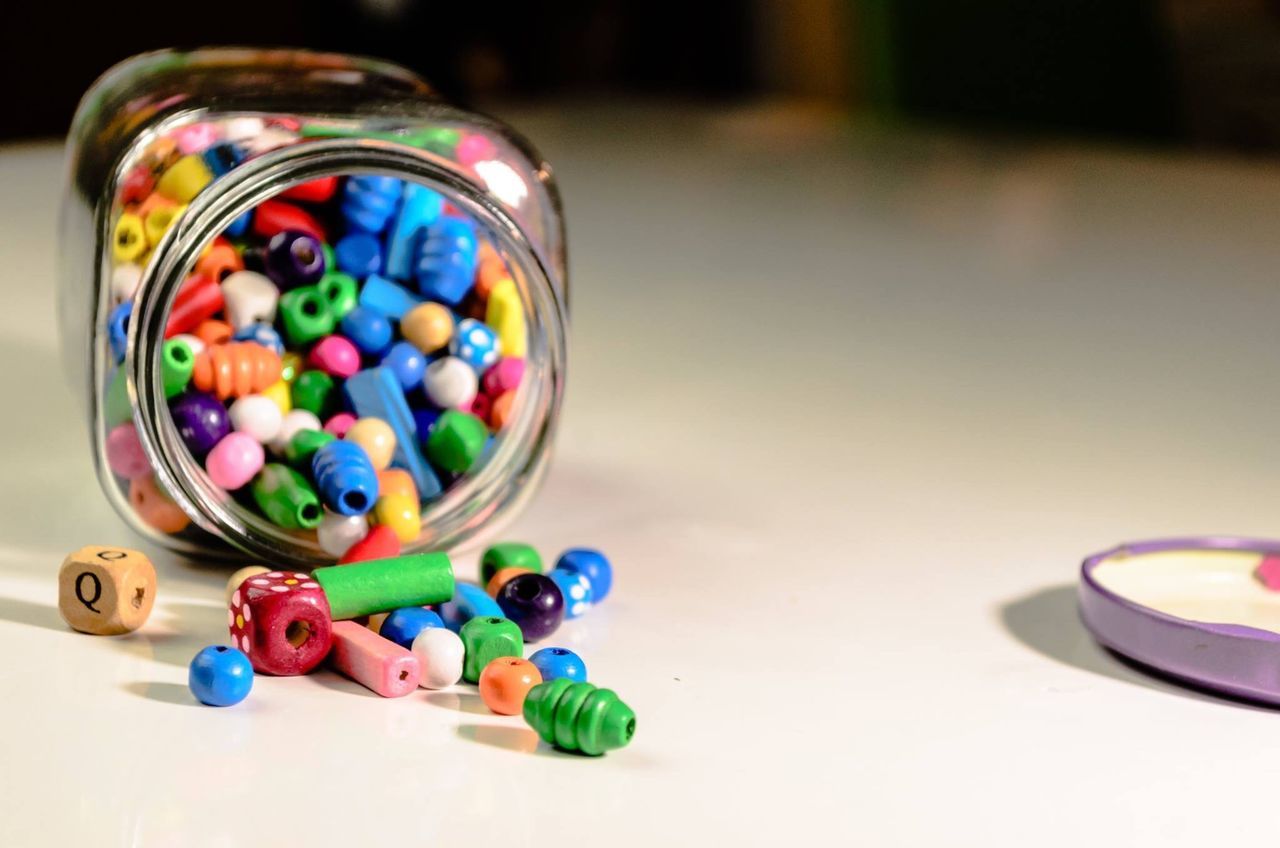 multi colored, large group of objects, indoors, still life, table, no people, close-up, choice, sphere, variation, marbles, focus on foreground, container, abundance, bead, collection, toy, art and craft, glass - material, selective focus, temptation, art and craft equipment