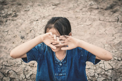 High angle view of girl sitting on arid field