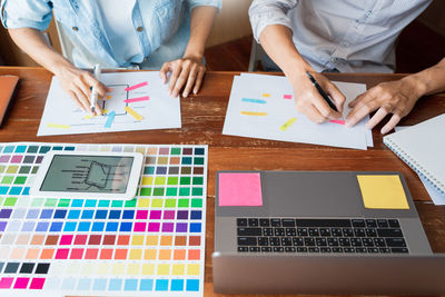 Midsection of design professionals working on desk in office