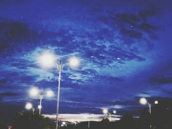 Low angle view of illuminated street light against blue sky