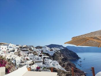 Townscape by sea against clear blue sky