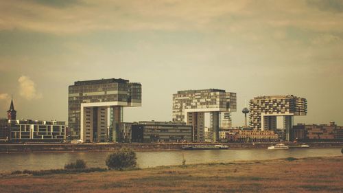 Buildings by river against sky in city