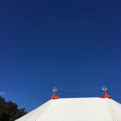 Low angle view of telephone pole against clear blue sky