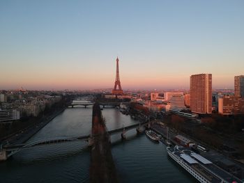 Bridge over river in city against sky during sunset