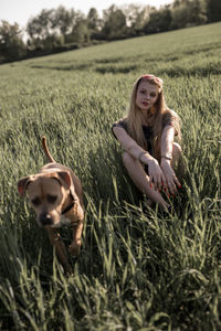 Young woman with dog sitting on grassy field