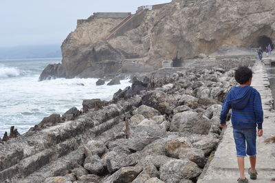 Woman standing on rock formation at seaside