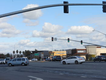 Vehicles on road against cloudy sky