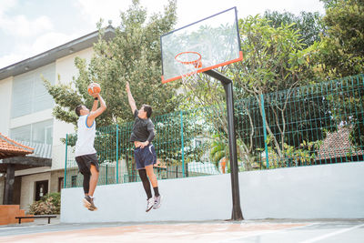 Men playing basketball hoop against clear sky