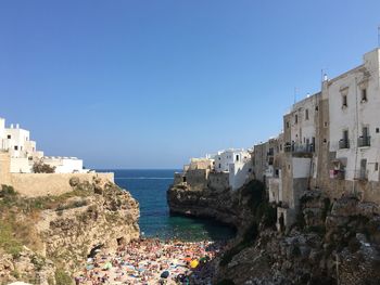 Buildings by sea against clear blue sky