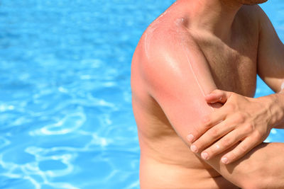 Midsection of shirtless man in swimming pool